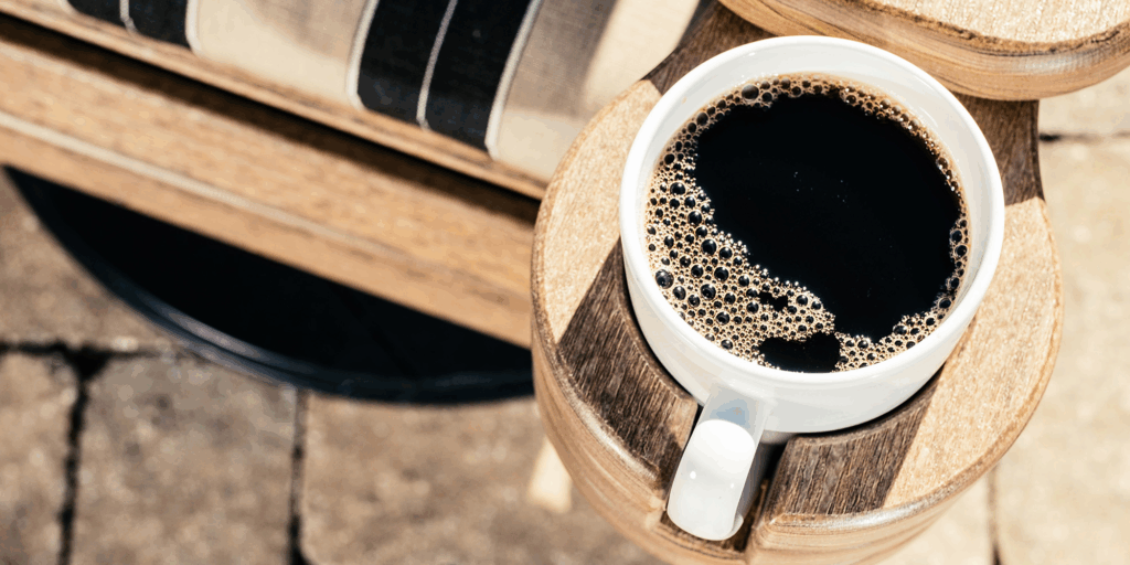 Coffee cup on outdoor side table, highlighting durable low-maintenance outdoor furniture lifestyle.